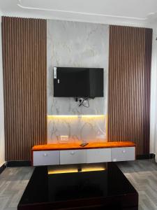 a living room with a television on a wall at Soana in Fort Portal +5 photos