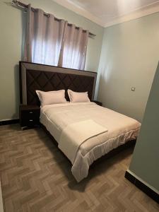 a bedroom with a large bed with white sheets and pillows at Soana in Fort Portal