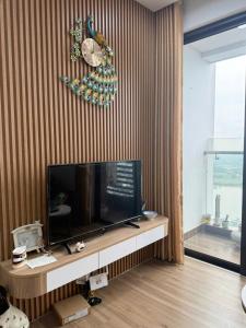 a living room with a television and a clock on the wall at Maison Joie Ecopark Lighthouse Ecorivers Hải Dương in Hải Dương