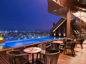 a rooftop bar with tables and chairs and a city skyline at Mercure Tangerang Centre in Tangerang