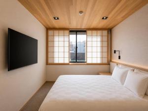 a bedroom with a bed and a tv on the wall at KIORI Collection Gokomachi in Kyoto