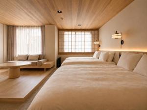 a bedroom with two beds and a couch and windows at KIORI Collection Gokomachi in Kyoto