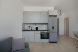 a kitchen with white cabinets and a refrigerator and a couch at Marilia Studios in Livadakia