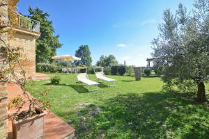 a yard with two white chairs and an umbrella at Fontesecca - Happy Rentals in Città della Pieve