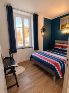a bedroom with a bed with blue walls and a window at La Garçonnière appartement climatisé in Charolles