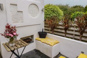 a bench on a balcony with a table and flowers at Penvar in Truro