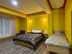 a bedroom with yellow walls and a bed and a window at Hotel Sonam Chen Residency Lachung in Lachung