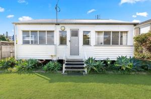a white house with a staircase in a yard at 30A Urangan Beach Cottage (Front Property) in Urangan