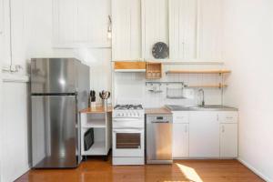 a kitchen with white cabinets and a stainless steel refrigerator at 30A Urangan Beach Cottage (Front Property) in Urangan +10 photos
