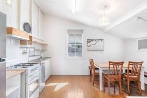 a white kitchen with a table and chairs in it at 30A Urangan Beach Cottage (Front Property) in Urangan