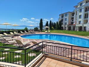 a swimming pool with chairs and umbrellas next to a building at Apartment Maraya 2, Carpe Diem complex, Balchik, free parking in Balchik