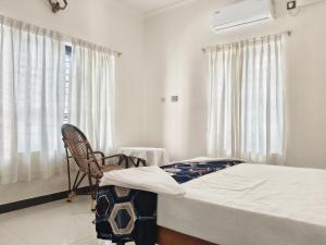 a bedroom with a bed and a chair and a window at Aromal Homestay in Kovalam