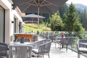a patio with tables and chairs and an umbrella at Hotel Zirbenhof in Hochfugen