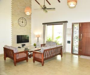 a living room with two chairs and a television at The Pentouz Hillside Chikmagalur in Chikmagalūr