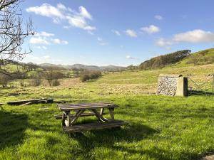 a wooden picnic table in a field with a fence at Ostlers End in Hartington
