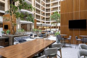 a lobby with tables and chairs and a flat screen tv at Embassy Suites by Hilton Minneapolis Bloomington Edina in Bloomington