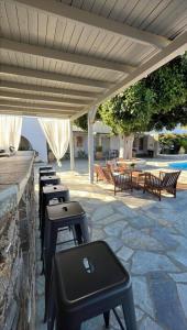 a row of stools sitting on a stone patio with at Paros Poolside Cozy Nests - Summer & Salty Getaways in Kalami