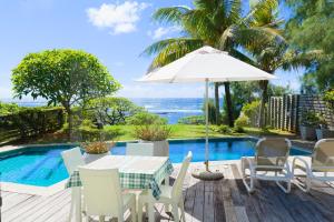 a table with an umbrella next to a swimming pool at Peter's Beach House in Poste Lafayette