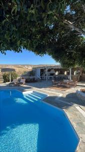 a blue swimming pool in front of a house at Paros Poolside Cozy Nests - Summer & Salty Getaways in Kalami