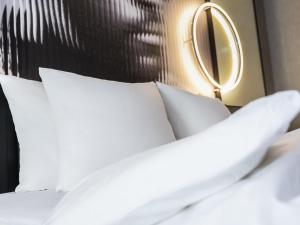 a bed with white pillows and a mirror on it at Tribe Amsterdam City in Amsterdam