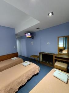 a room with two beds and a tv on the wall at Hotel cirse cr in Comodoro Rivadavia