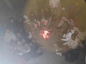 a group of people sitting around a fire at Raghupur trecking camp in Shoja