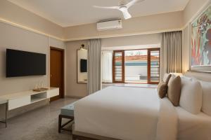 a bedroom with a large white bed and a television at Oasis County Villas in Bangalore