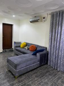 a living room with a blue couch with colorful pillows at PLV Apartment in Ilorin