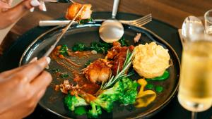 a plate of food with broccoli and meat on a table at Skojet Boutique Hotel in Ruhengeri +18 photos