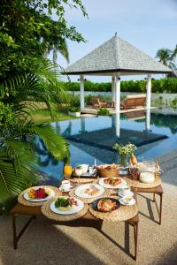 a table with food on it next to a pool at Twin Villas Natai - North & South Villa - Luxury Beach Front Villa - 6 Br Full Service in Natai Beach
