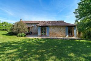 a small stone house with a grass yard at Gite Le Mas in Corgnac-sur-lʼIsle