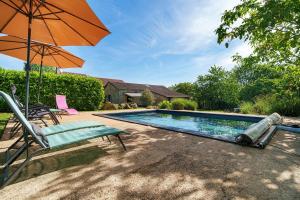 a swimming pool with a chair and an umbrella at Gite Le Mas in Corgnac-sur-lʼIsle