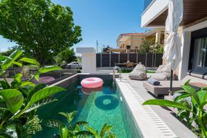 a backyard swimming pool with a pink frisbee in it at Trithiron Luxury Villas in Nea Moudania