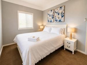a bedroom with a white bed and a window at Anita Cottage waterfront in Lake Munmorah