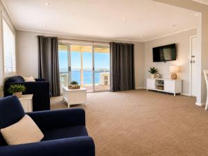 a living room with a blue couch and a television at Anita Cottage waterfront in Lake Munmorah