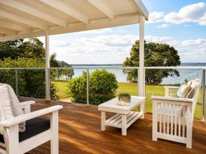 a porch with chairs and a table and a view of the water at Anita Cottage waterfront in Lake Munmorah