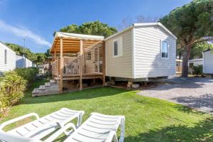 a tiny house with white chairs in a yard at Bungalow in Canet-en-Roussillon