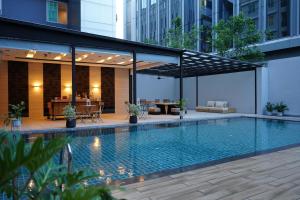 a swimming pool with a pavilion next to a building at Arize Hotel Sukhumvit in Bangkok
