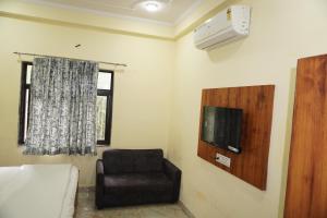 a bedroom with a chair and a tv and a bed at Hotel Moon Mahal in Jaipur
