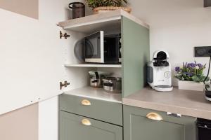 a kitchen with white cabinets and a microwave at Studio Cocoon in Colombey-les-Belles