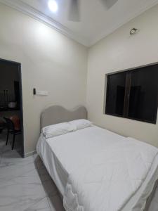 a white bedroom with a bed and a television at Shareen Homestay Morib in Banting