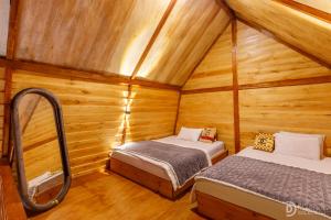 a room with two beds in a wooden cabin at Villa Ira Dieng in Diyeng
