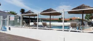 a swimming pool with chairs and umbrellas on the side at le 130 mobile home à Meschers sur Gironde au camping L'escale in Meschers-sur-Gironde
