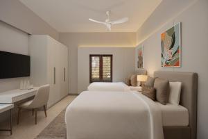 a bedroom with two beds and a desk and a tv at Oasis County Villas in Bangalore