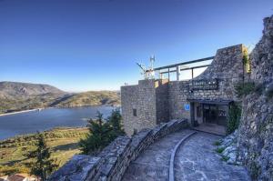 a building on the side of a mountain next to a river at Hotel Tugasa Arco de la Villa in Zahara de la Sierra