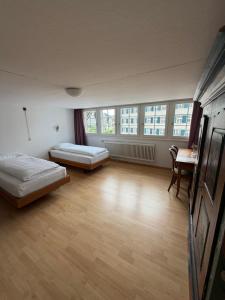 a room with two beds and a table and windows at Krone Trogen in Trogen