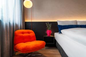 a bedroom with a orange chair next to a bed at Savoy Hotel in Frankfurt