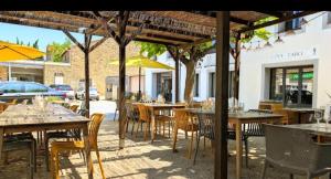 an outdoor restaurant with tables and chairs and umbrellas at La Maison de Valerie Feng Shui in La Livinière