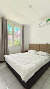 a bedroom with a large bed with white sheets at Villa Dalia Puncak N5-10 in Cikundul