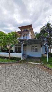 a large white house with a tree in front of it at Villa Dalia Puncak N5-10 in Cikundul